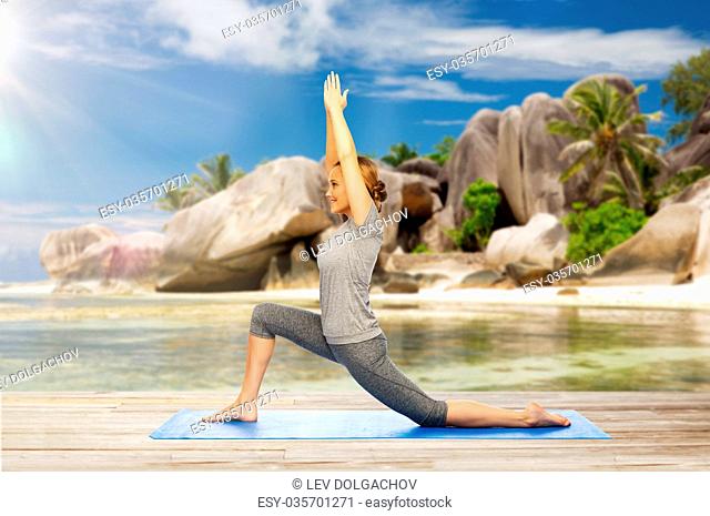 fitness, sport and people concept - happy woman doing yoga in low lunge pose on mat over exotic tropical beach background