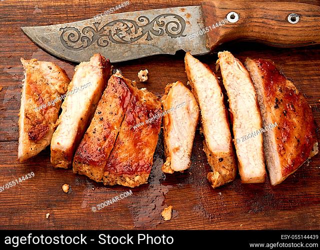 fried pork steak sliced on stripes on a kitchen cutting board, juicy well-fried meat, top view