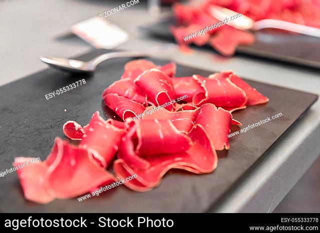 Italian bresaola beef thinly sliced and served on black stone board. Perfect appetizer. Used for party, wedding or other