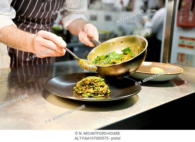 Restaurant chef placing cooked lentil dish on plate