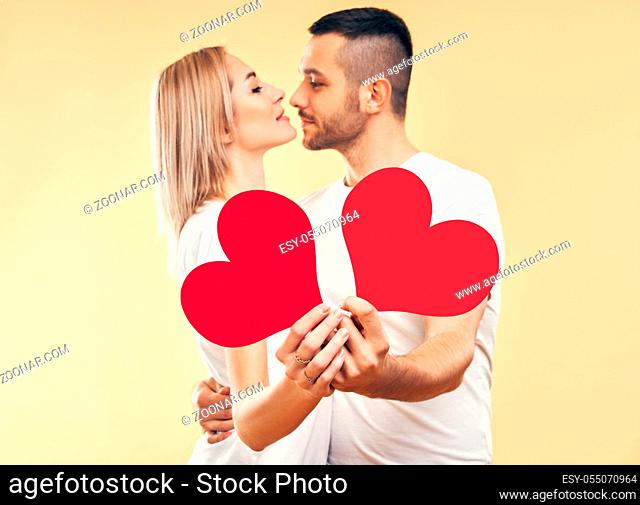 Young couple in love holding big paper hearts in hands over studio background. relationship concept