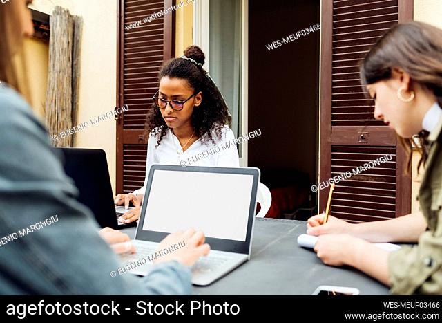 Businesswoman using laptop while working with colleague at terrace