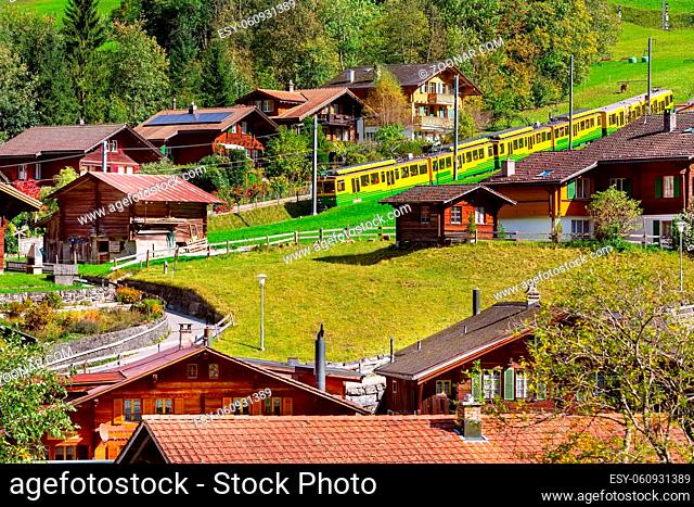 Lauterbrunnen, Switzerland alpine wooden houses in Swiss Alps village in autumn and wengernalpbahn train