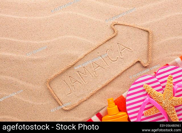 Jamaica pointer and beach accessories lying on the sand, as background
