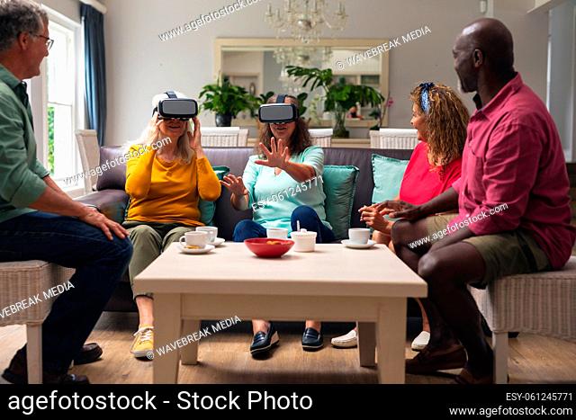 Multiracial senior woman and men with friends using vr headsets at home