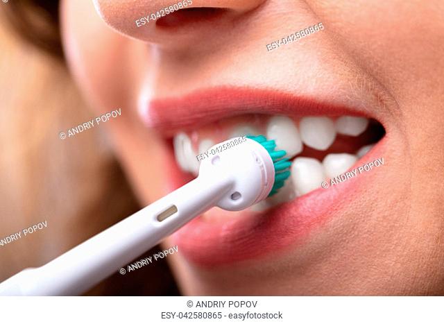 Close-up Of A Woman's Hand Brushing Teeth With Electric Toothbrush