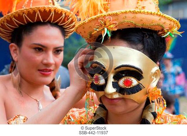 UK, England, London, Young woman preparing masked Bolivian participant for Carnival Del Pueblo, Carnaval Del Pueblo Festival is Europes Largest Latin Street...