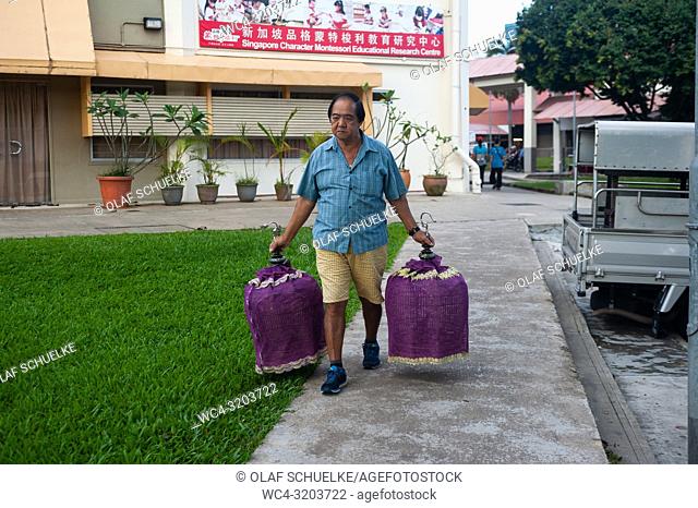 02. 12. 2018, Singapore, Republic of Singapore, Asia - An elderly bird lover is carrying two of his birdcages on an early morning to the Kebun Baru Bird Corner...