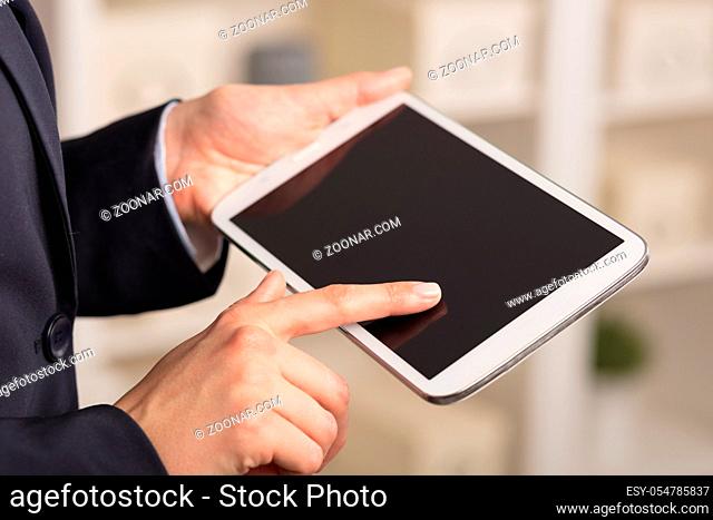 Business woman below chest using tablet in a homey environment