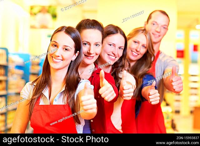 Erfolgreiche Supermarkt-Mitarbeiter halten lachend die Daumen hoch