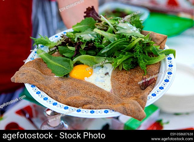 Freshly prepared food is seen close up on a plate during an outdoor food fair, fresh salad with fried egg served in a wrap as a healthy meal