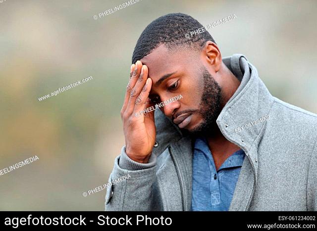 Worried man with black skin complaining in winter walking in a park