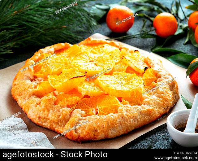 Close up view of caraway and orange tart on baking paper over black cement background. Winter season and christmas ideas recipe - tart with caraway pastry and...