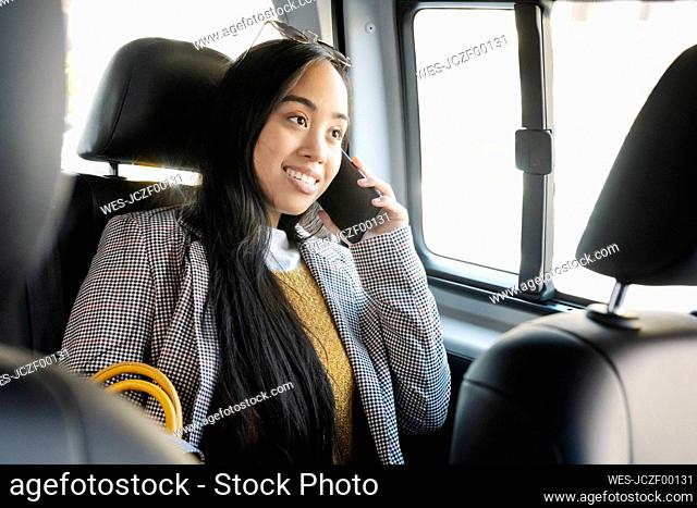 Young woman talking over smart phone while sitting in car