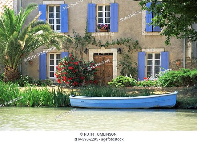 Boat moored alongside house on the bank of the Canal du Midi, Le Somail, Aude, Languedoc Roussillon, France, Europe