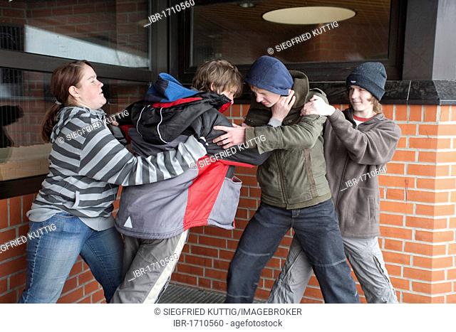 Two boys fighting on the playground while two other teenagers are trying to get them apart, posed scene
