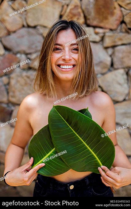 Happy woman with leaves in front of wall