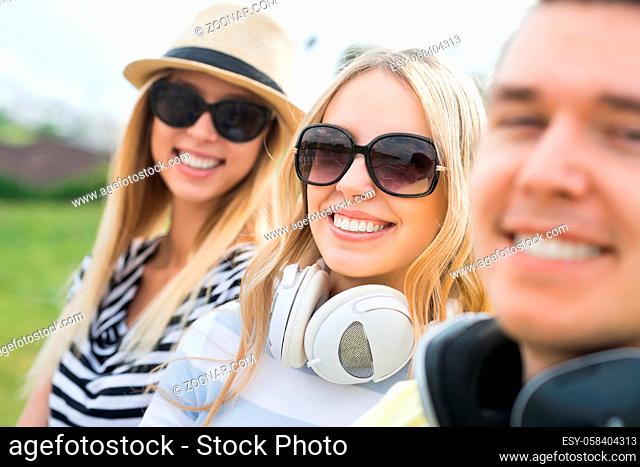 Three young happy people sitting on staircase and enjoying summer day