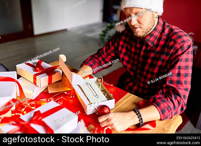 DIY, Man in Santa hat making greeting card for New Year and Christmas for friends or family , packing presents or gifts, mail manager concept