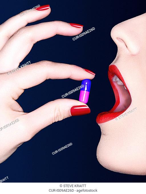 Close up of woman's mouth with bright lipstick and pill