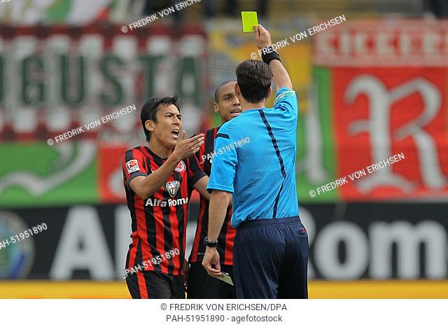 Referee Frankfurt's Manuel Gräfe (front, back view) shows Frankfurt's Bamba Anderson (L) the yellow card as his teammate Makoto Hasebe tries to appease during...