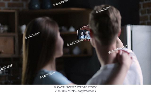 Positive couple taking selfie together at home