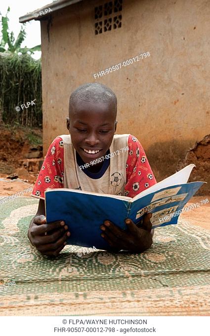Child reading from educational book at home, Rwanda