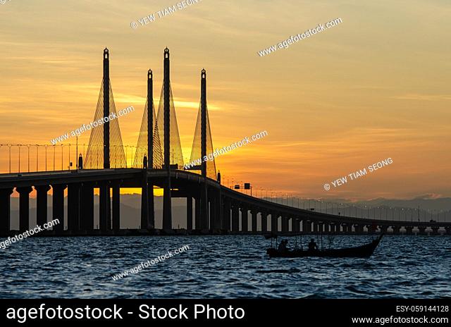 Silhouette fishing boat near Penang Second Bridge during sunrise