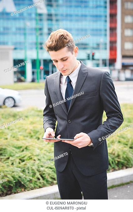 Portrait of young businessman commuter using digital tablet