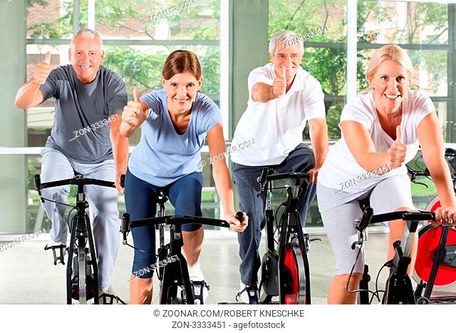 Senioren im Sportkurs im Fitnesscenter halten ihre Daumen hoch
