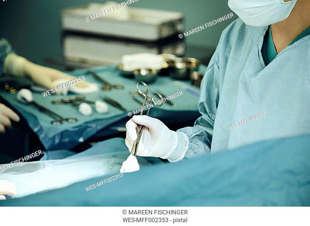 Surgeon holding clamp in operating room during surgery