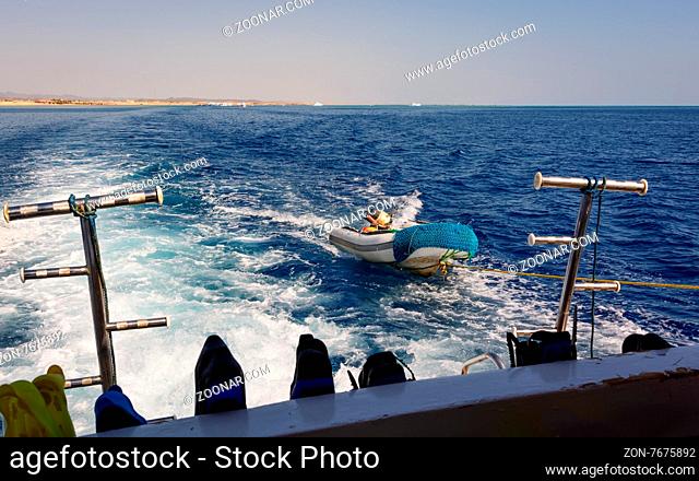 In the picture a moving ship , docked with a speedboat , at forward hooked flippers and masks for snorkeling and in the background Egyptian coast