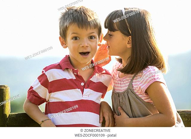 Little girl whispering secret in the ear of her boyfriend