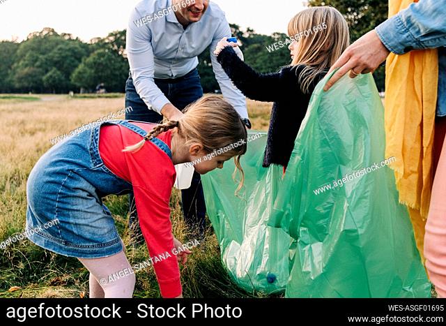 Daughters helping parents collecting garbage in park