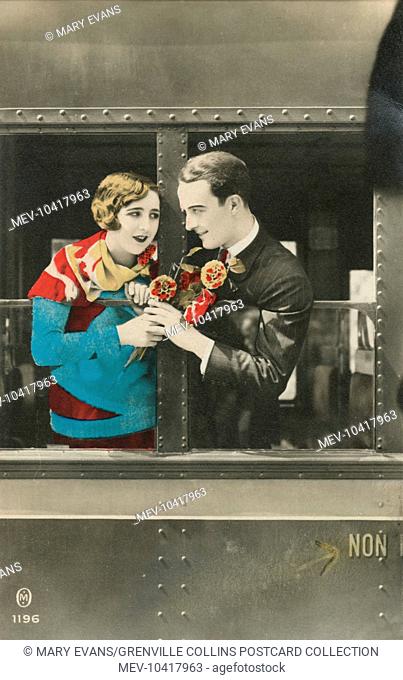 A couple sharing a tender moment between two windows of a stationary railway carriage. Their locked gaze is testament to the success of his charm offensive