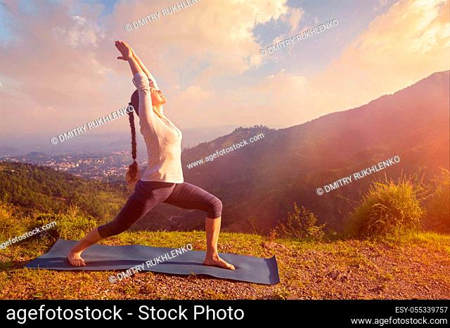 Yoga outdoors - sporty fit woman doing yoga asana Virabhadrasana 1 - Warrior pose posture outdoors in Himalayas mountains in the morning