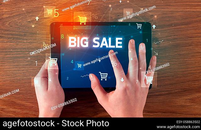 Close-up of a hand holding tablet with BIG SALE inscription, online shopping concept
