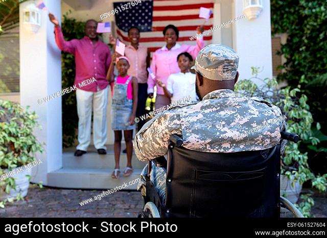 African american soldier father in wheelchair greeting smiling three generation family outside home