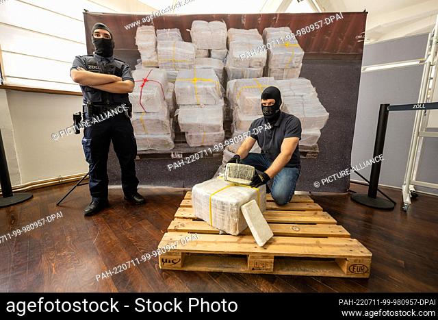 11 July 2022, Bavaria, Munich: A customs officer kneels in front of part of what has become the largest single seizure of cocaine in Bavaria to date