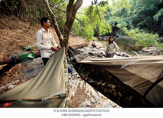 Guide helping tourists to set up camp along the O Chbar river. Dey Ei Trek, Mondulkiri, Cambodia