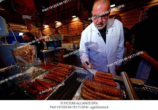 05 December 2019, North Rhine-Westphalia, Cologne: On behalf of the City of Cologne, food inspector Oliver Maier checks the temperature of sausages at a stand...