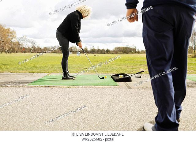 Friends practicing golf at driving range