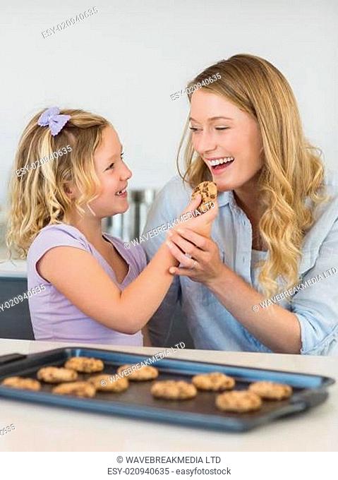 Girl feeding cookie to mother