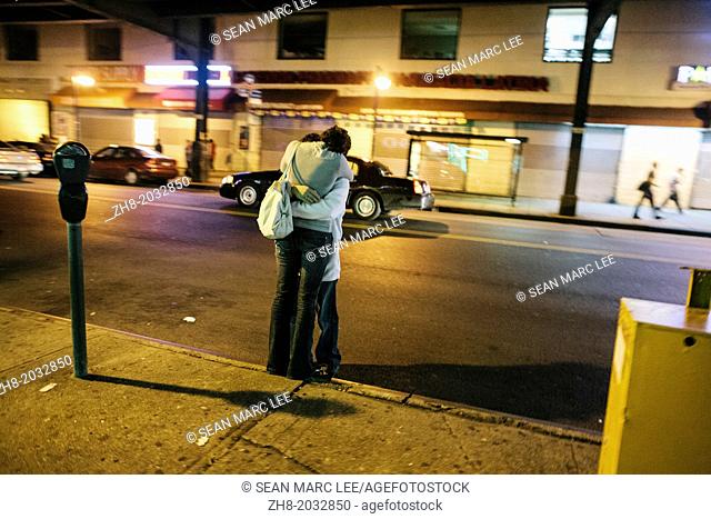 A couple embraces on the street at night in Queens, New York