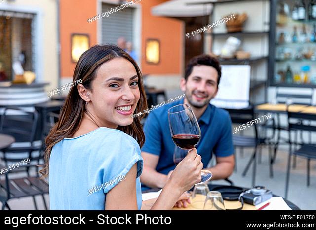 Happy woman having wine with boyfriend at sidewalk cafe