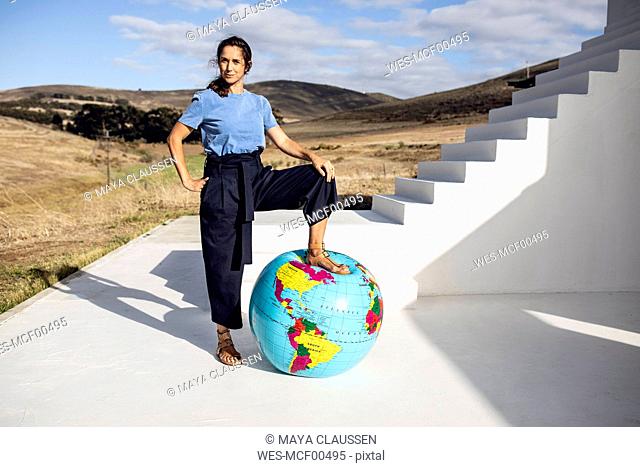 Confident woman putting foot on inflatable globe