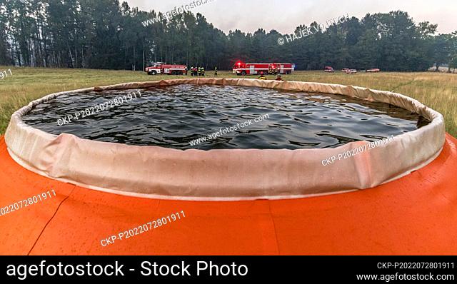 Helicopters get water to Bambi Bucket from a special 54.5-cubic-meter bag located near the fire and filled from tankers, Hrensko in the Ceske Svycarsko (Czech...