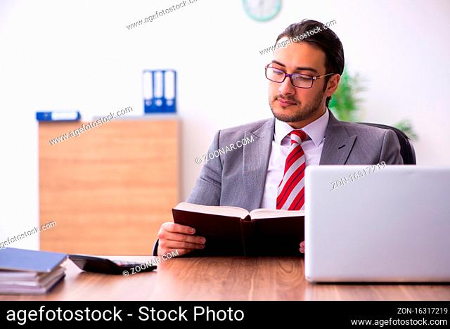 Male employee reading book in the office