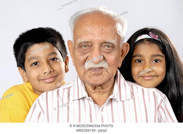 South Asian Indian grandfather with grandchildren looking at camera MR152