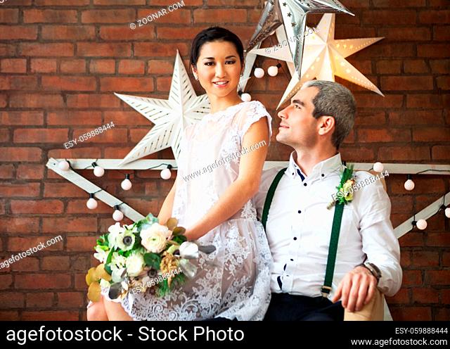 Cheerful married couple standing near the brick wall decorated with the stars